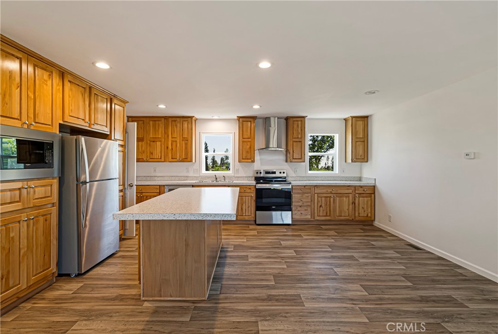 5352 Sawmill Road Paradise, CA 95969 - Photo 8 of 23 a large kitchen with stainless steel appliances wooden floor and wooden cabinets