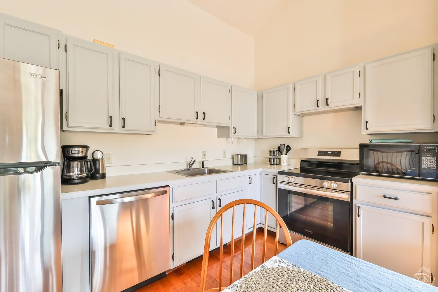 28-1 Loo Bridge Lane, Unit 22A Windham, NY 12496 - Photo 21 of 35 a kitchen with stainless steel appliances granite countertop a stove top oven a refrigerator a sink and white cabinets with wooden floor