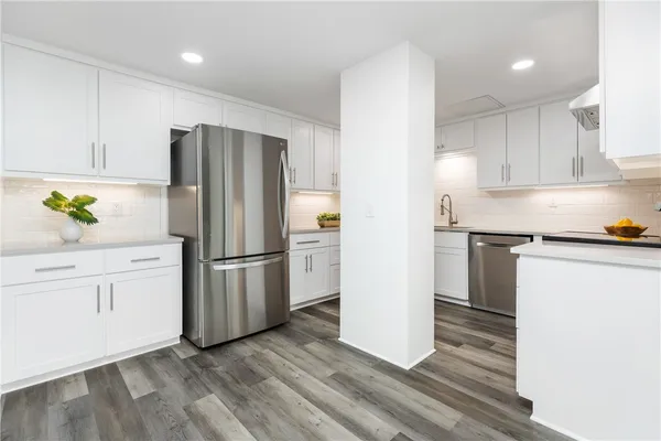 a kitchen with stainless steel appliances a refrigerator a sink a stove and white cabinets