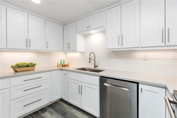 a kitchen with white cabinets and sink