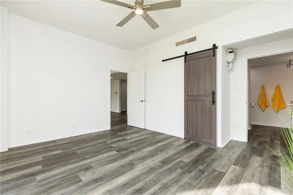 a view of a hallway with wooden floor and a ceiling fan
