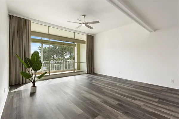 a view of empty room with wooden floor and fan