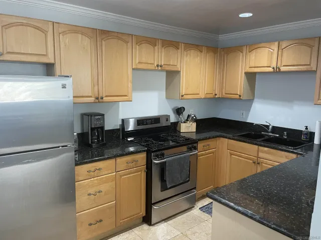 a kitchen with granite countertop a sink stove and cabinets