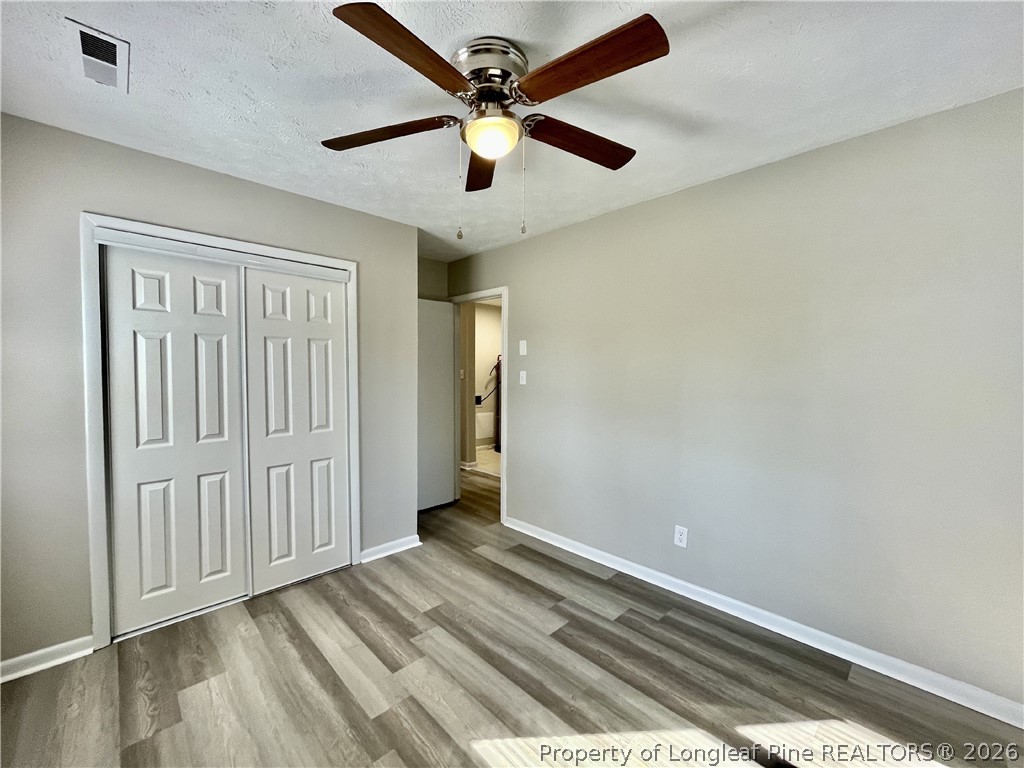 5985 McDonald Road Parkton, NC 28371 - Photo 15 of 20 an empty room with wooden floor ceiling fan and windows