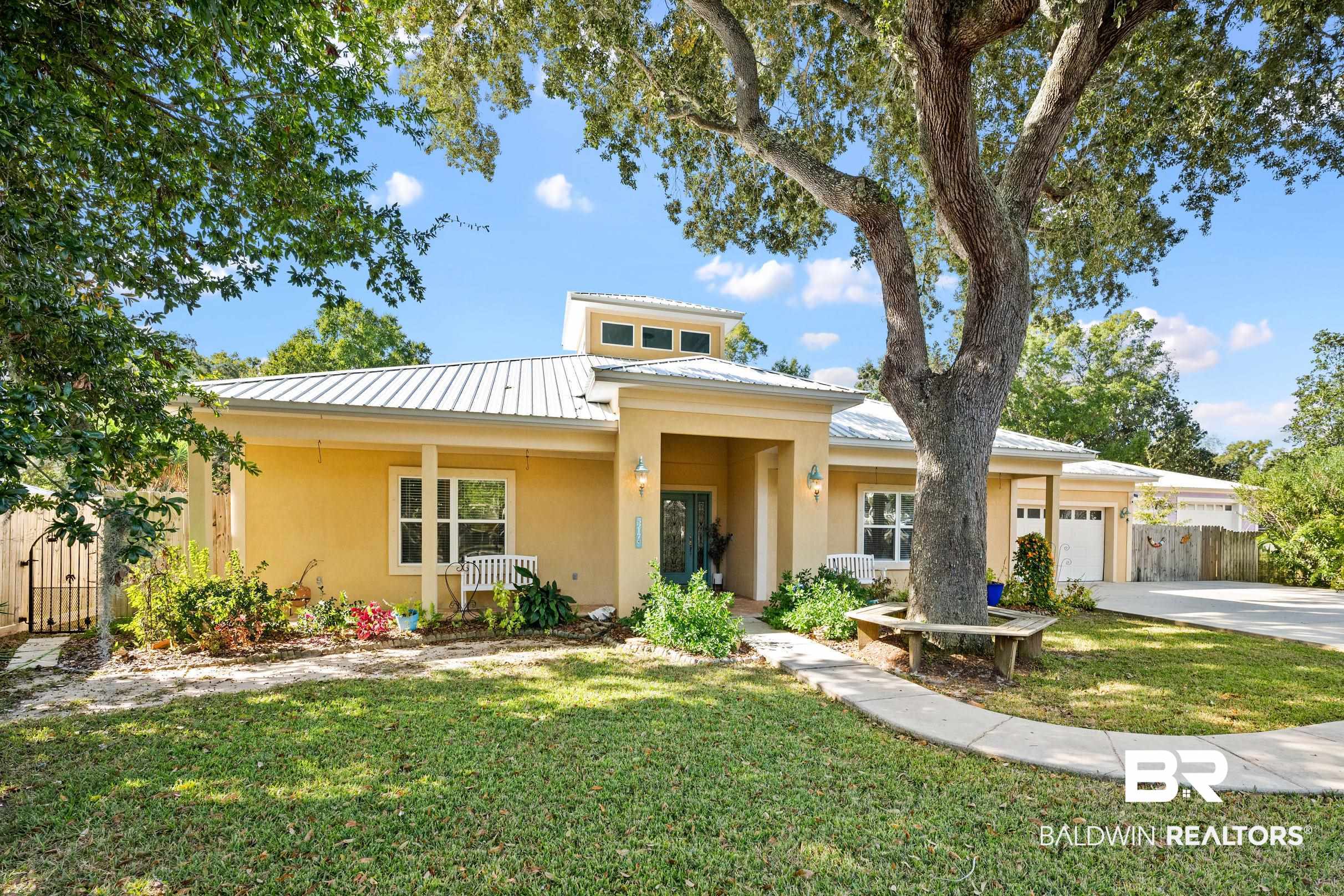 View of front facade featuring a metal roof, stucco siding, a garage, concrete driveway, and covered porch