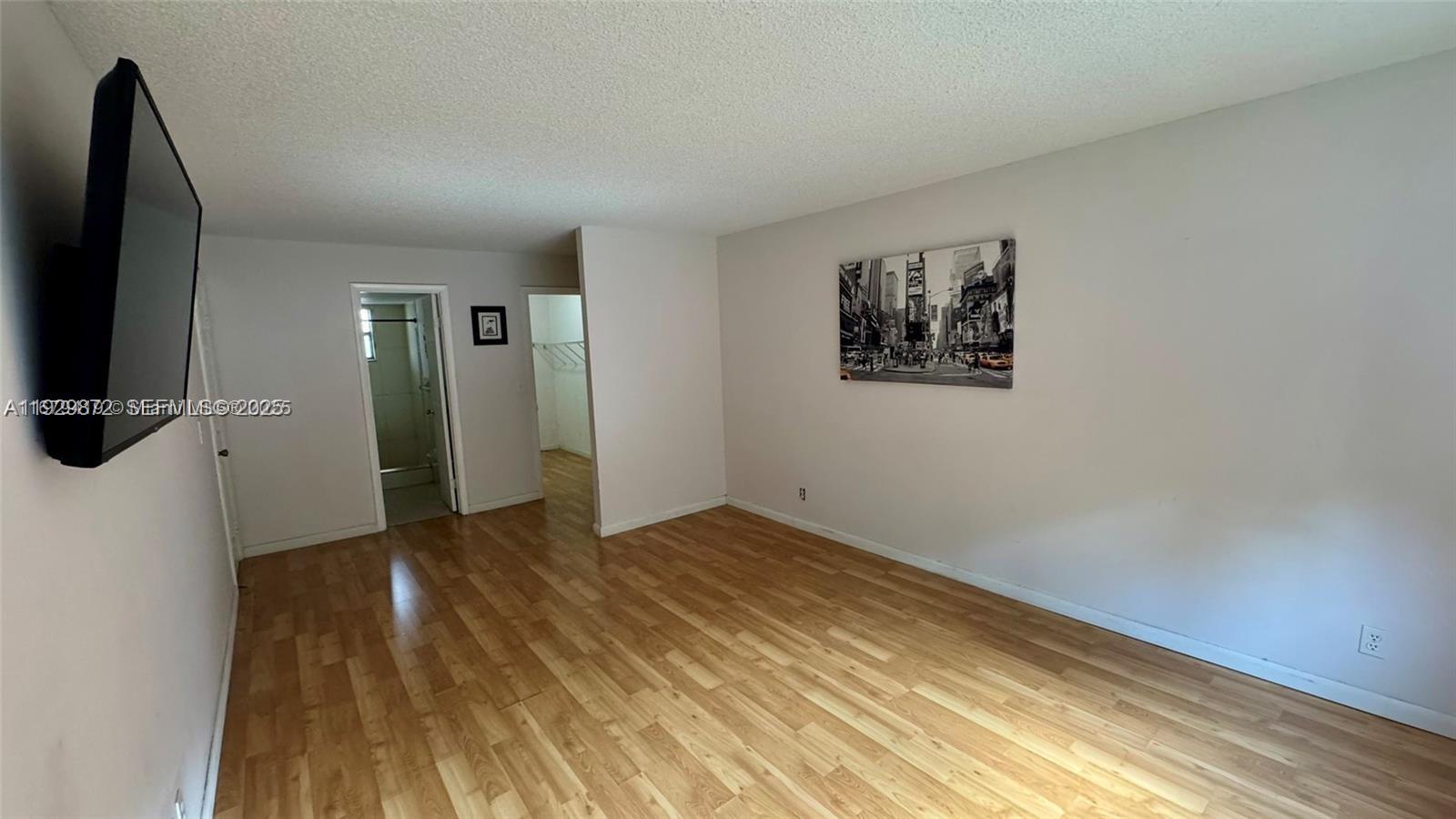 7060 Nova Drive, Unit 306C Davie, FL 33317 - Photo 11 of 17 a view of an empty room with wooden floor and a flat screen tv
