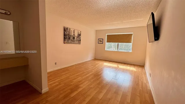 a view of an empty room with wooden floor and a flat screen tv