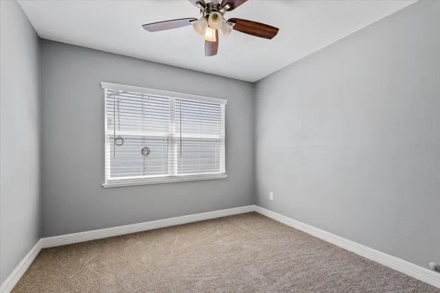an empty room with a window and a fan