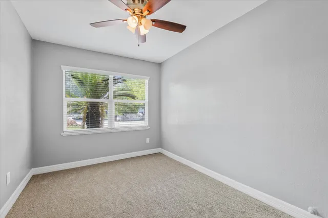 an empty room with a window and a fan