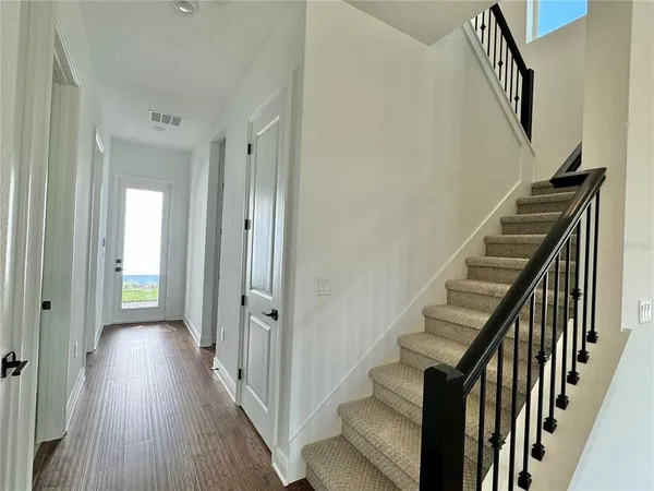 a view of a hallway with wooden floor and staircase