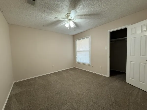 an empty room with chandelier fan and windows