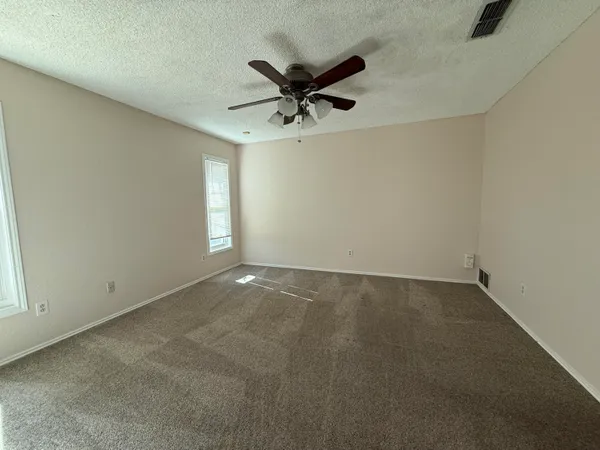 an empty room with a ceiling fan and window