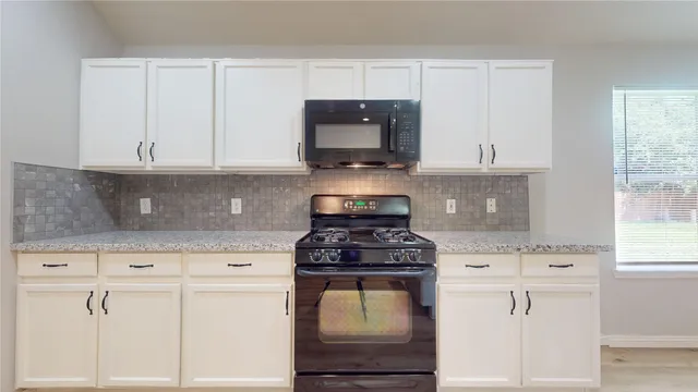 a kitchen with granite countertop white cabinets and white appliances