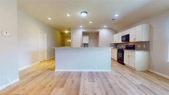 a view of kitchen with kitchen island wooden floor center island and stainless steel appliances