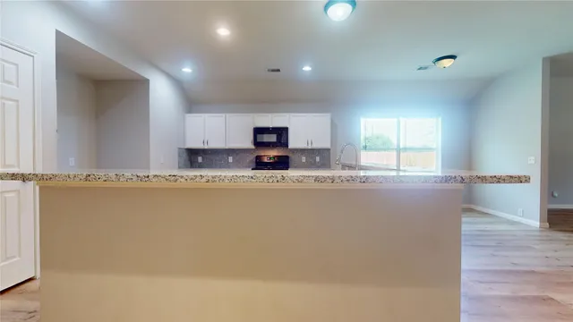 a large white kitchen with kitchen island a sink wooden floor and a counter top space