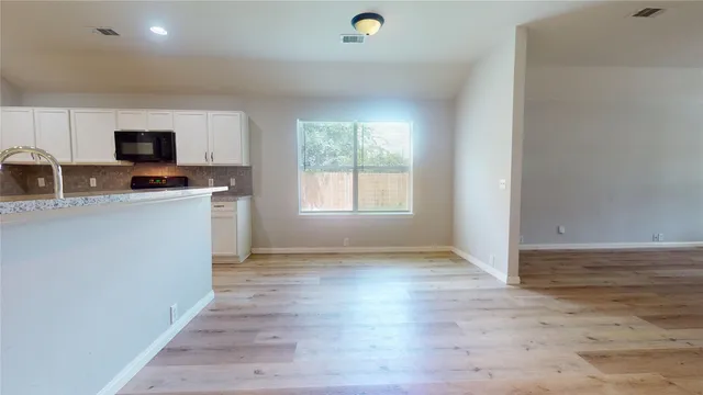 a view of a kitchen with a sink a microwave and a window