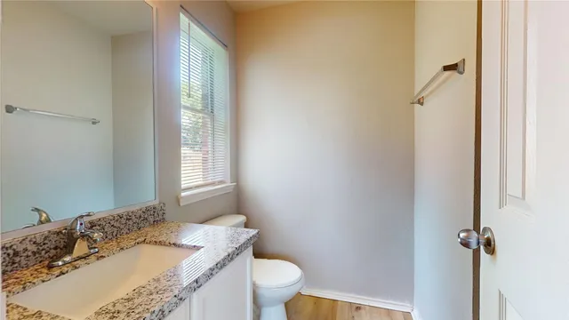 a bathroom with a granite countertop sink toilet and a mirror