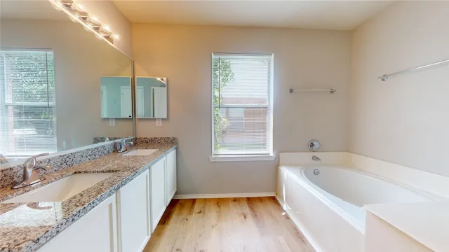 a bathroom with a granite countertop tub sink and mirror