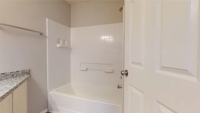 a white bath tub sitting next to a white sink and vanity
