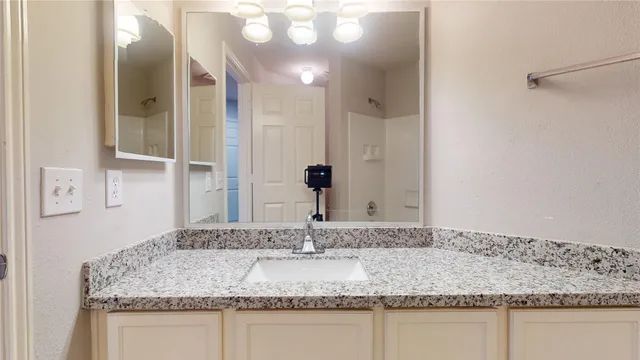 a bathroom with a granite countertop sink and a mirror
