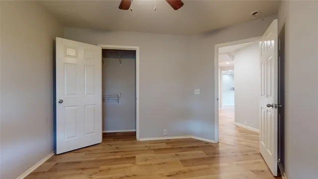 a view of an empty room with wooden floor and closet