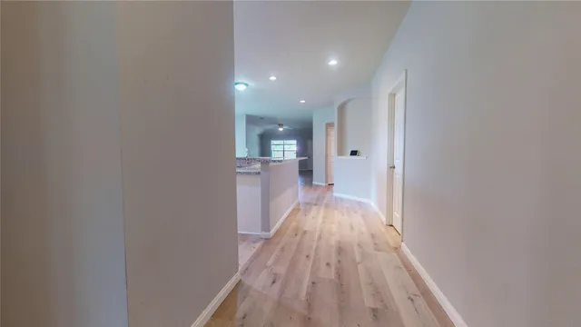 a view of a hallway with wooden floor and a bathroom
