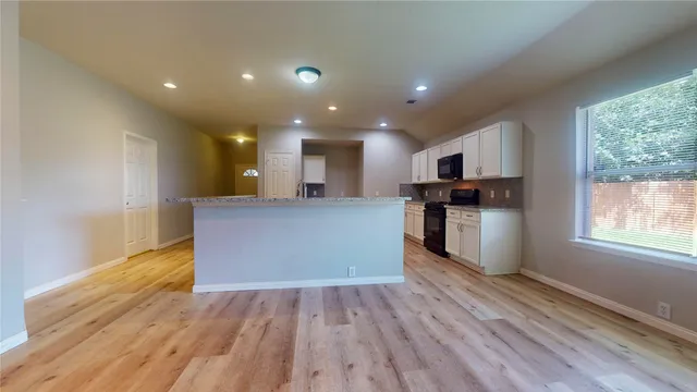 a view of kitchen with kitchen island wooden floor center island and stainless steel appliances