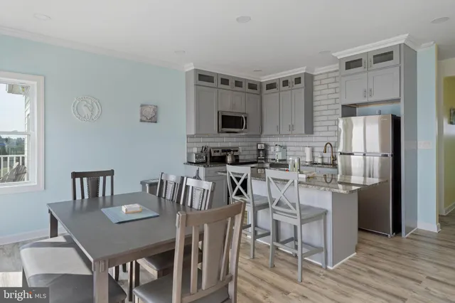 a kitchen with stainless steel appliances granite countertop a dining table chairs refrigerator and sink