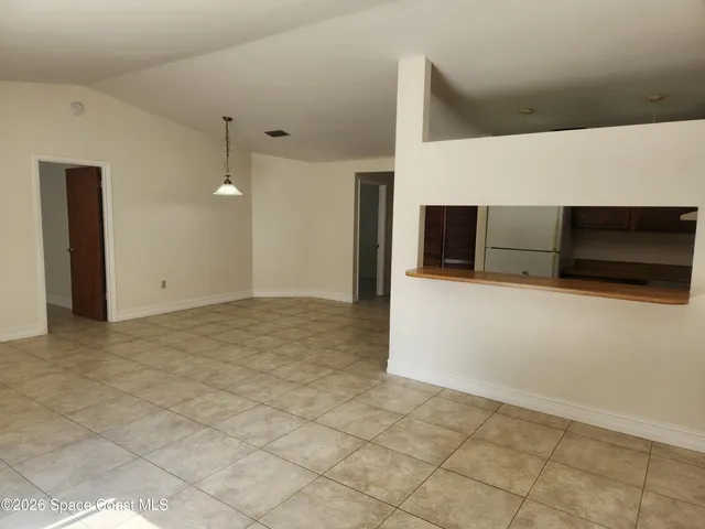a view of an empty room with kitchen and a window