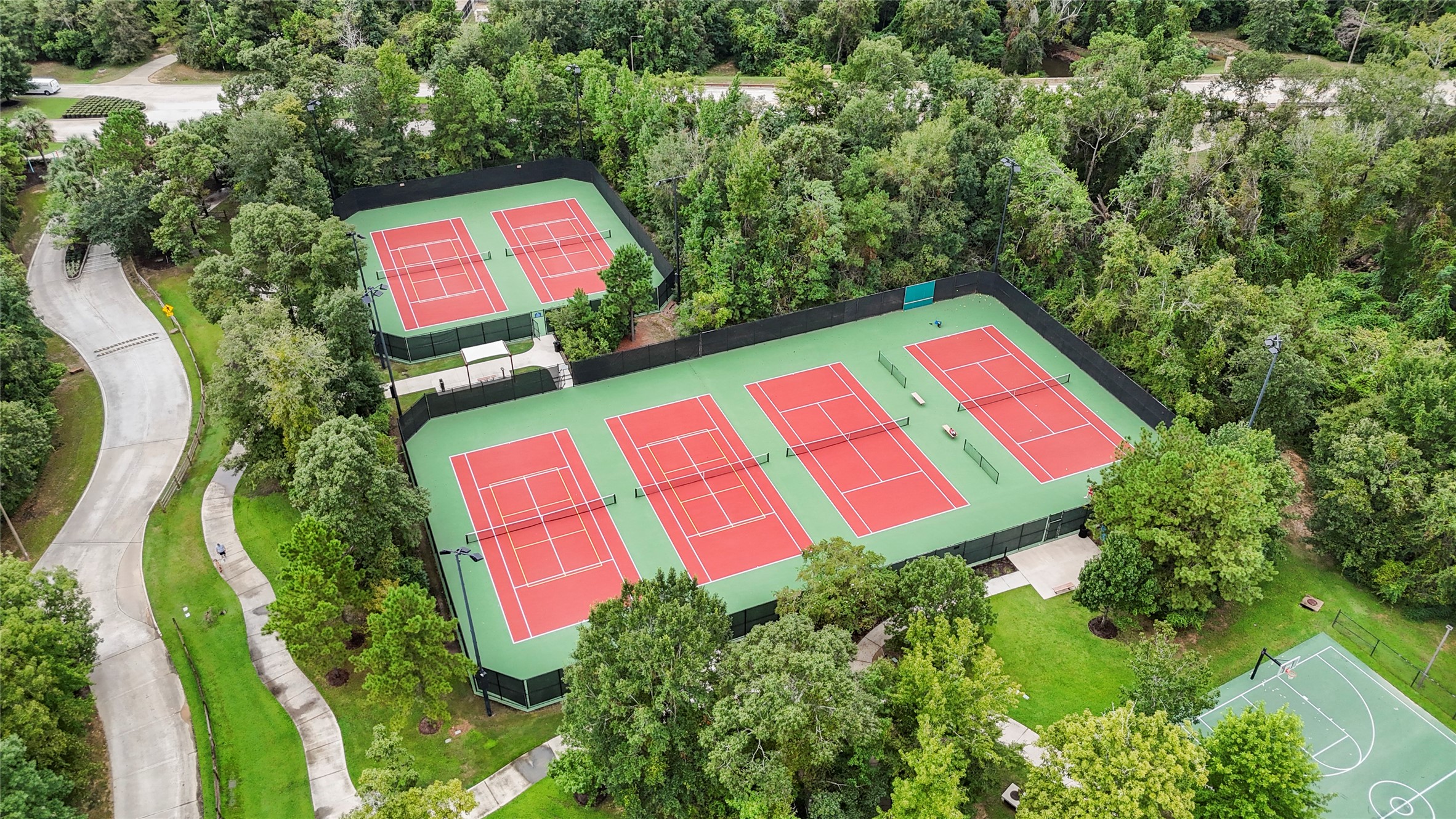 334 Topper Pines Drive Montgomery, TX 77316 - Photo 45 of 49 From above, Woodforest’s tennis and pickleball courts show just how much recreation is woven into the community, with walking paths, open green space, and trees surrounding another active outdoor amenity.