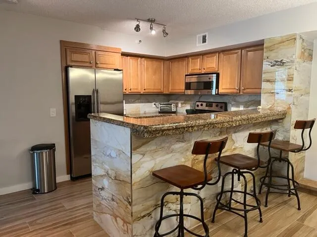 a kitchen with stainless steel appliances granite countertop a stove refrigerator sink and cabinets