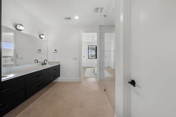 a spacious bathroom with a double vanity sink a mirror and shower