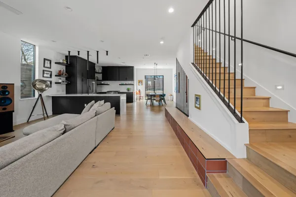 a living room with stainless steel appliances furniture a flat screen tv and a wooden floor