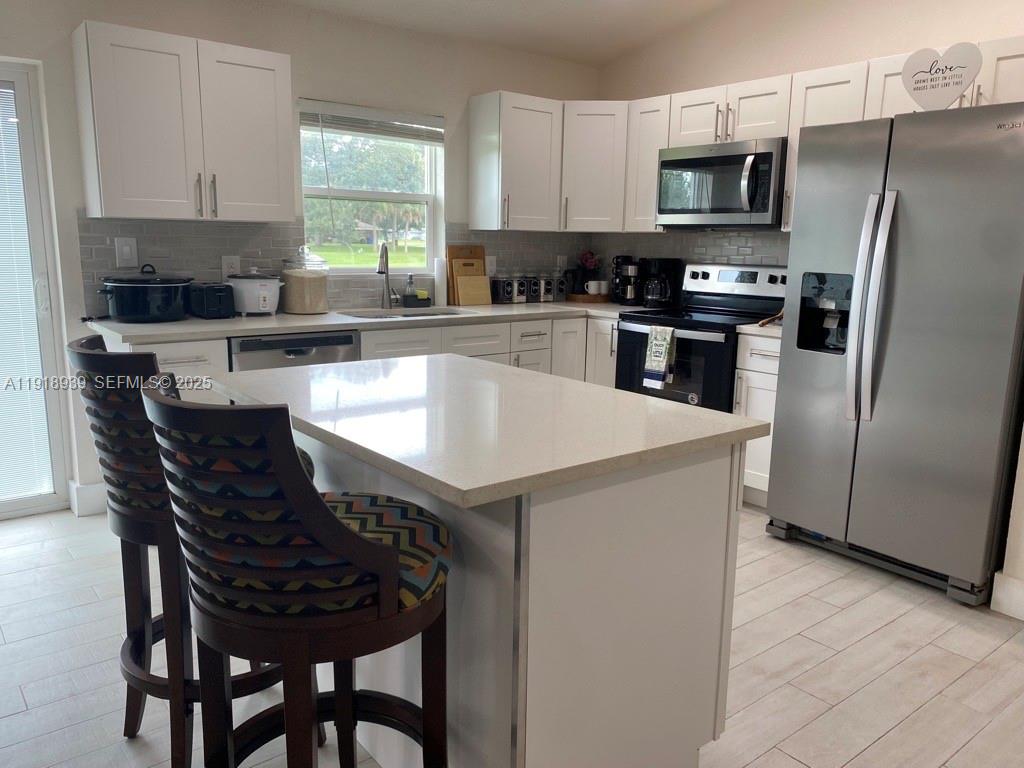 417 Cherry Tree Drive Sebring, FL 33876 - Photo 8 of 26 a kitchen with stainless steel appliances a table chairs sink refrigerator and microwave