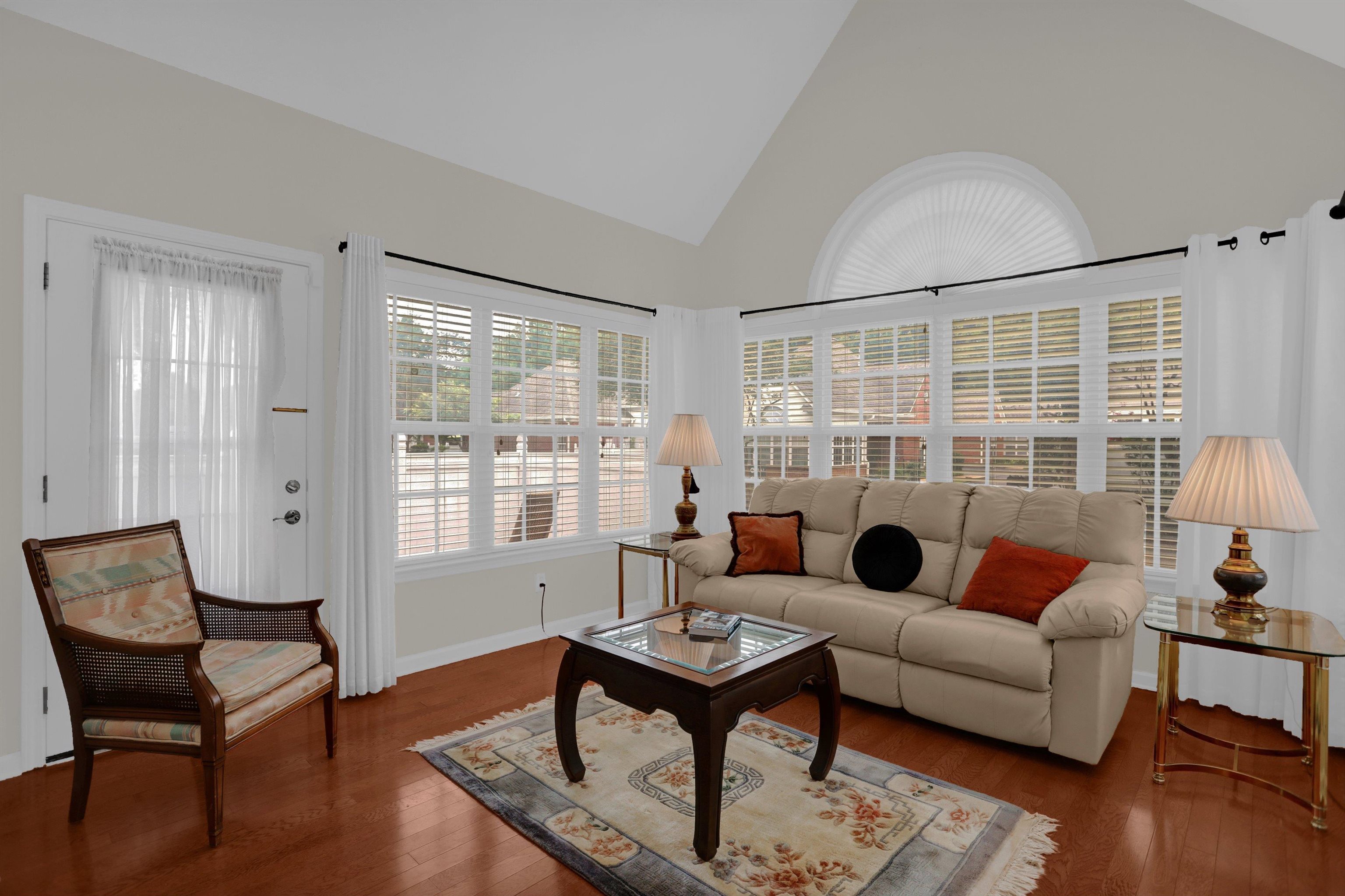 34 Peyton Ridge Drive, Unit 21 Collierville, TN 38017 - Photo 9 of 37 Bright living area featuring vaulted ceilings, wood-finish flooring, multiple paneled windows with blinds, and an arched transom window