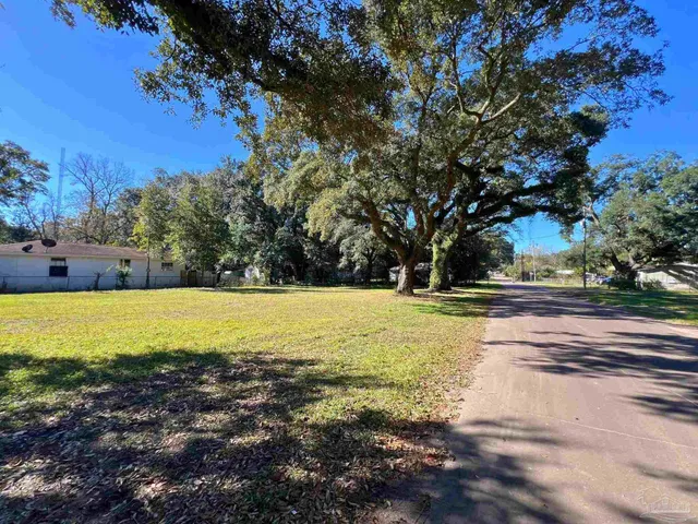 a view of a house with a big yard and large trees
