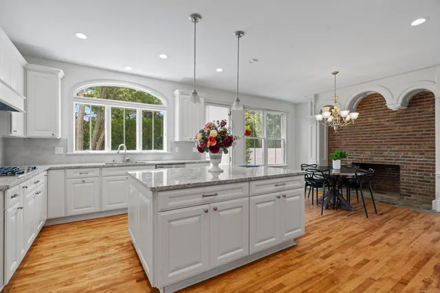 a kitchen with kitchen island granite countertop a stove a sink a dining table and chairs with wooden floor