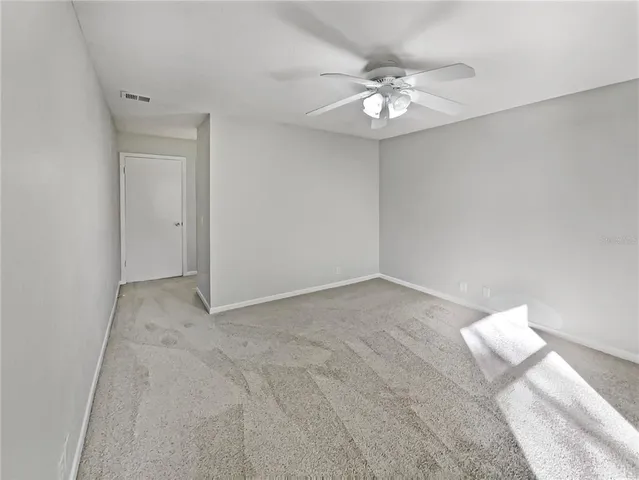 a view of an empty room with a chandelier fan