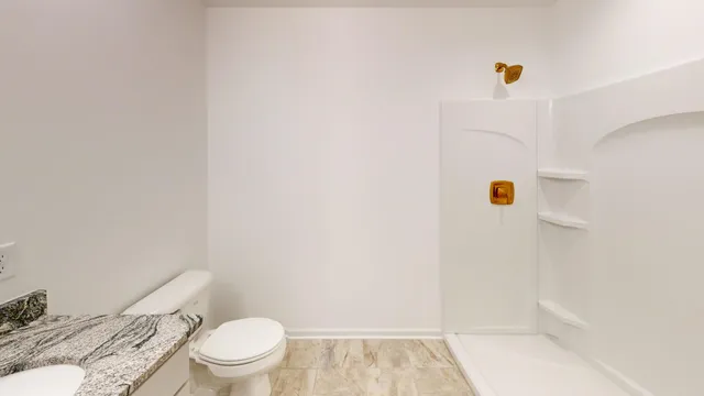 a white toilet sitting next to a white wall