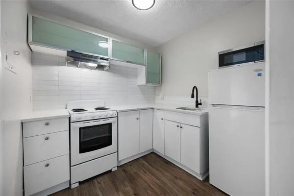 a kitchen with a stove and a wooden floor