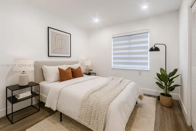 a bedroom with bed plant and window