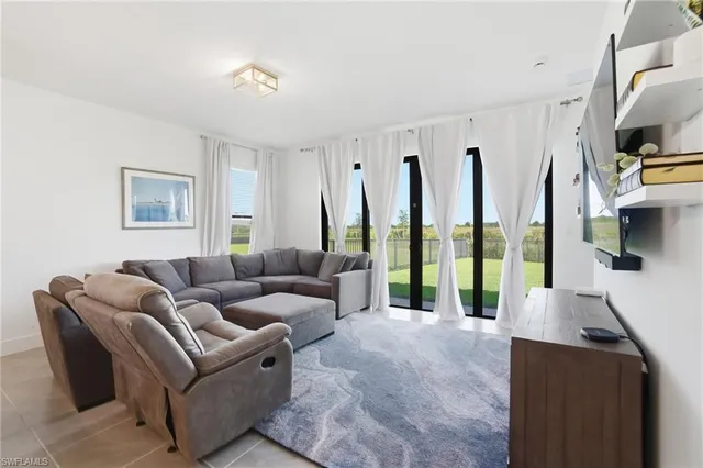 a living room with furniture a flat screen tv and a large window