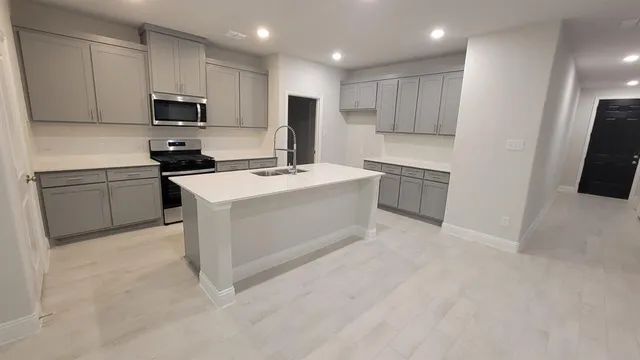 a kitchen with stainless steel appliances granite countertop a stove top oven a sink and a refrigerator