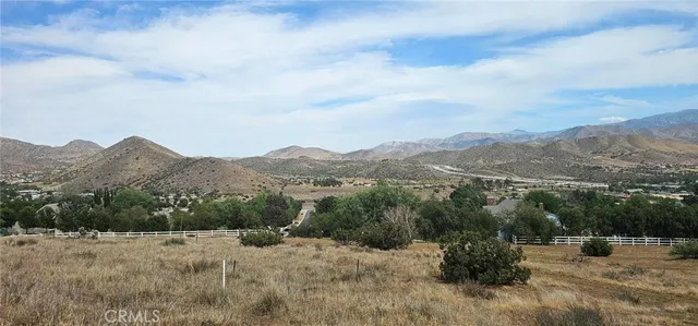 a view of a dry field with mountains in the background