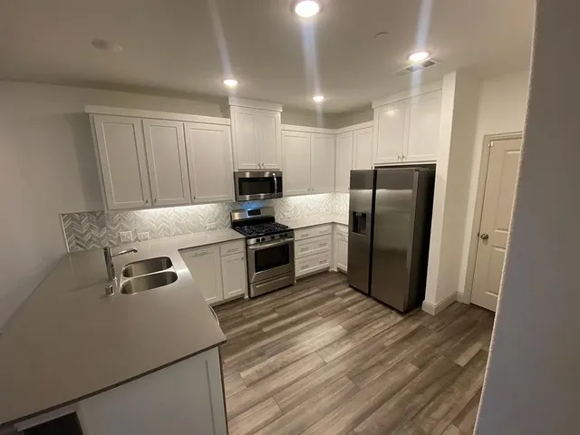 a kitchen with a refrigerator a stove and wooden floor