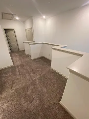 an empty room with chandelier fan and windows