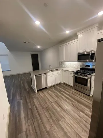 a large kitchen with stainless steel appliances a large counter top a stove and a refrigerator