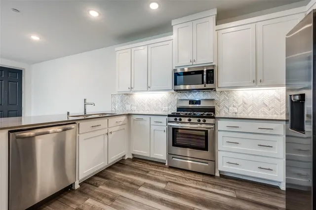 a kitchen with granite countertop white cabinets and stainless steel appliances