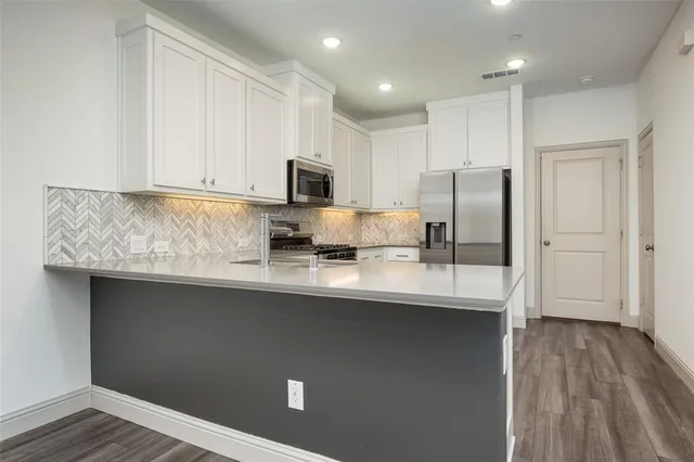 a kitchen with kitchen island granite countertop a sink refrigerator and microwave