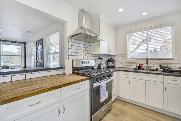 a kitchen with stainless steel appliances granite countertop a stove a sink and white cabinets